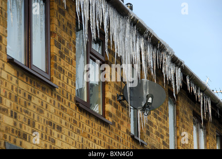 Un sacco di grandi ghiaccioli appesi da un tetto e antenna satellitare. Oxfordshire, Regno Unito, 2010. Foto Stock