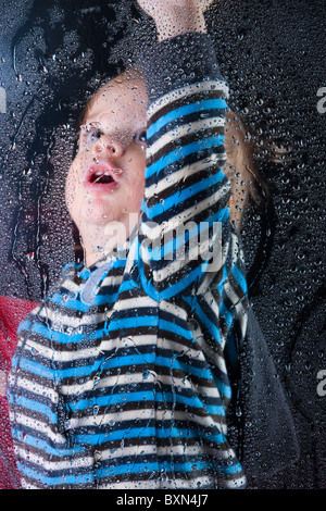 Little Boy gioca con la formazione di condensa sulla finestra Foto Stock