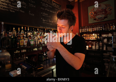 Giovane barista accendere una sigaretta dietro il bancone di un bar Foto Stock