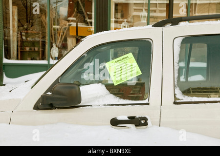 Mezzo sepolto nella neve piccola auto è contrassegnati con parcheggio violazione per bloccare la pulizia della strada dopo New York City blizzard Foto Stock