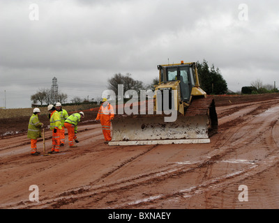 Ingegneria civile i lavoratori con un bulldozer sulla costruzione di strade site uk in inverno Foto Stock