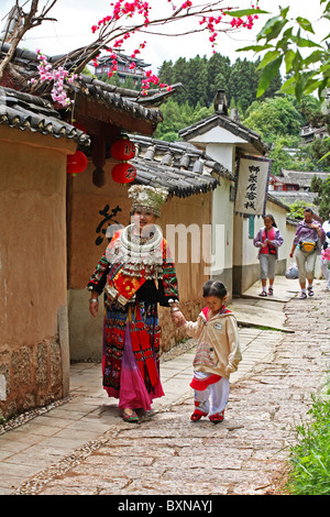 Donna che indossa costumi tradizionali cammina con il bambino intorno a Lijiang Vecchia, provincia di Yunnan, Cina Foto Stock