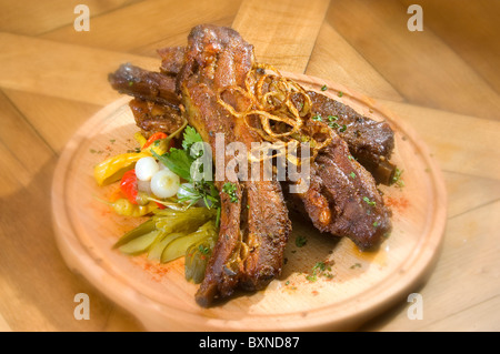 Costolette alla griglia w pickle e cipolla sul piatto di legno Foto Stock