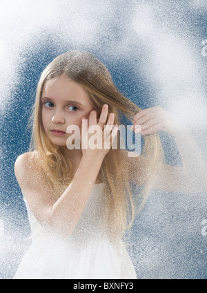 Vista attraverso la finestra della ragazza di toccare i capelli Foto Stock