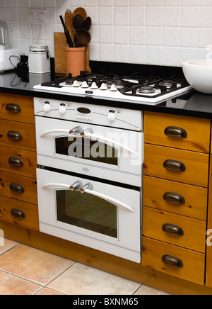 Architettura interni domestici bianco fornelli a gas e forno elettrico elettrodomestico impostato al di sotto del piano di lavoro in cucina attrezzata Foto Stock