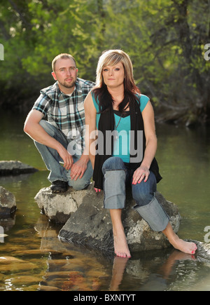 Drammatica giovane bella giovane seduto sulle rocce in fiume Foto Stock