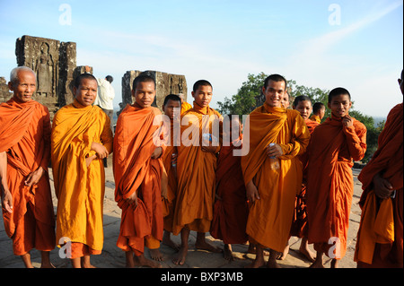 I monaci buddisti giovani e vecchi si radunano alla sommità di una collina a guardare il tramonto sopra i templi di Angkor a Siem Reap, Cambogia. Foto Stock