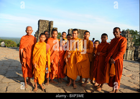I monaci buddisti giovani e vecchi si radunano alla sommità di una collina a guardare il tramonto sopra i templi di Angkor a Siem Reap, Cambogia. Foto Stock