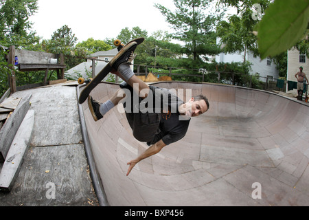 Guidatore di skateboard vola attraverso l'aria trucchi di preformatura su una rampa da skateboard in Charlottesville, VA. Foto Stock