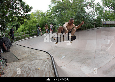 Guidatore di skateboard vola attraverso l'aria trucchi di preformatura su una rampa da skateboard in Charlottesville, VA. Foto Stock