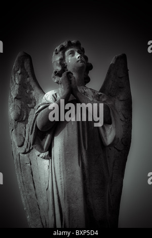 Weathered stone monumento funebre di un angelo che prega. Foto Stock