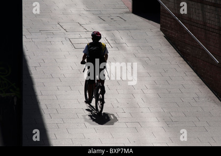 Un ciclo di equitazione di corriere da solo su una stretta strada di città Foto Stock