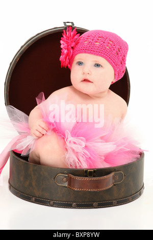 Bella 4 mese fa American baby ragazza seduta in caso di viaggio su sfondo bianco. Foto Stock