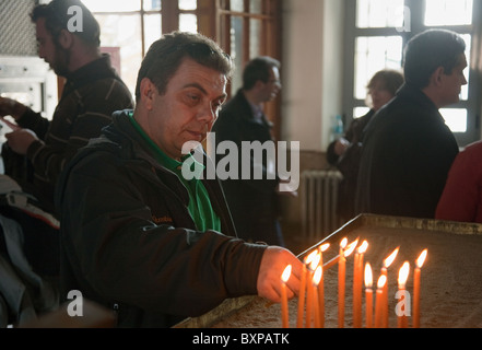 Credente accendere una candela in chiesa, Heybeliada, Turchia Foto Stock