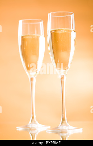 Immagine di due flauti piena di frizzanti champagne su sfondo arancione Foto Stock