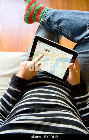 Uomo in un momento di relax a casa utilizzando un Apple iPad a cercare su Google maps sul suo giro. Foto Stock