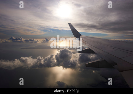 Guardando fuori sopra le nuvole attraverso la finestra di jet di linea Foto Stock