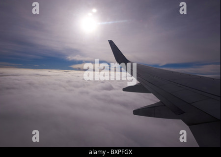 Guardando fuori sopra le nuvole attraverso la finestra di jet di linea Foto Stock