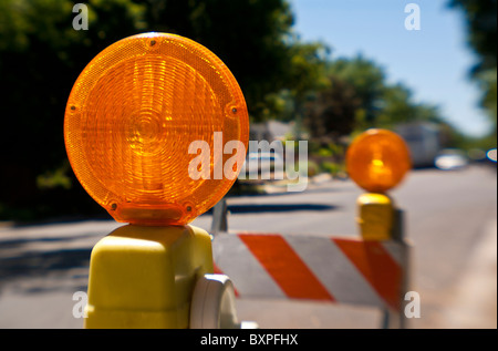 Arancione lampade attenzione sulla cima di colore arancione e bianco barricate di traffico Foto Stock