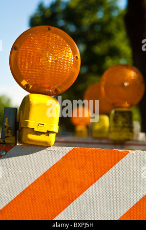 Arancione lampade attenzione sulla cima di colore arancione e bianco barricate di traffico Foto Stock