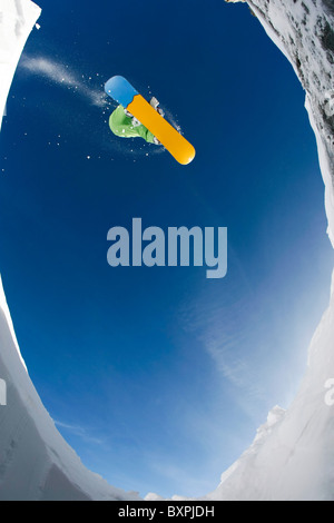 Al di sotto di vista sportivo godendo lo snowboard sullo sfondo del cielo blu Foto Stock