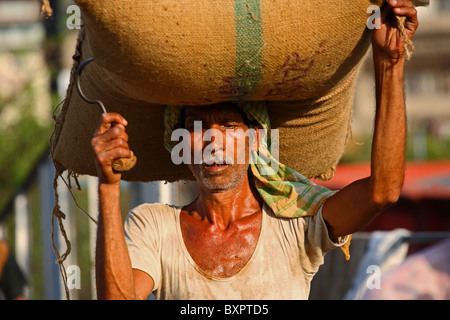 Indian l uomo si porta il peso sulla testa di Calcutta, in India Foto Stock