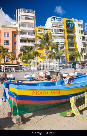 Vista di Las Canteras beachfront in Las Palmas de Gran Canaria con una colorata barca da pesca in primo piano. Foto Stock