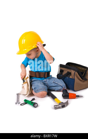 Un giovane ragazzo che indossa un elmetto e cinghia ATTREZZO, giocando con cresciuti gli strumenti. Foto Stock