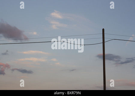 Silhouette di un palo del telegrafo al crepuscolo contro un cielo blu Foto Stock