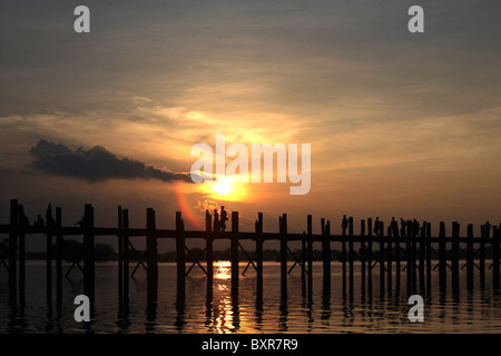 I monaci che attraversa la U Bein ponte in teak, che abbraccia Taugthaman Lago in Amarapura vicino a Mandalay in Myanmar (Birmania) Foto Stock