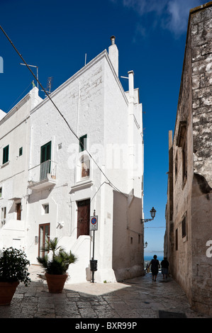 Vicolo tra alti edifici della città vecchia di Ostuni, Puglia, Italia Foto Stock