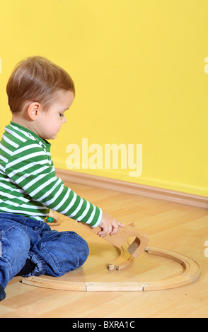 Carino toddler caucasica giocando con il trenino in asilo nido. Testo supplementare dello spazio sul angolo superiore destro. Foto Stock