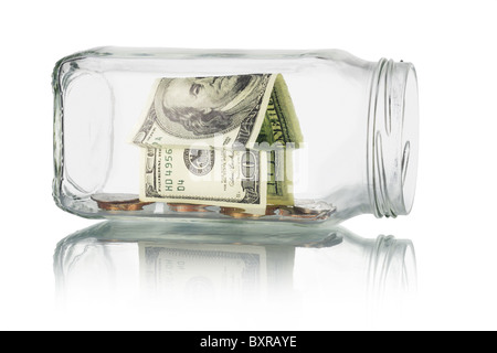 I risparmi e gli investimenti - casa di denaro e monete in un barattolo di vetro su sfondo bianco Foto Stock
