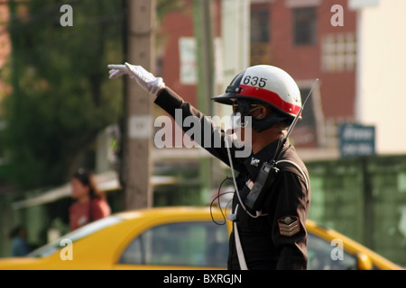 Un poliziotto sta soffiando un fischio mentre indirizzare il traffico su una strada trafficata a Bangkok, in Thailandia. Foto Stock