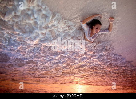 Giovane donna giacente in surf sulla spiaggia al tramonto Foto Stock