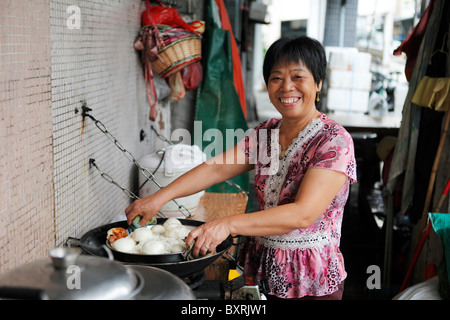 Residente locale gnocchi di cuochi per la colazione su Av de Demetrio Cinatti, vicino al mercato del pesce, Macao Foto Stock
