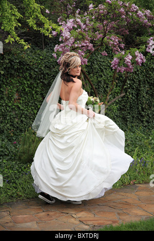 Bella bionda sposa camminare in giardino percorso in abito da sposa Foto Stock