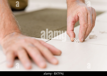 Home Improvement - close-up di tuttofare collocando il distanziale di piastrelle Foto Stock