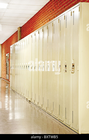 Colpo in prospettiva di una fila di armadietti nel corridoio di un muro di mattoni scuola. Foto Stock