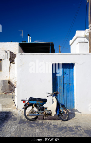 Arrugginito scooter Yamaha parcheggiato di fronte di una tipica casa delle Cicladi in Marmara, sul Greco Cyclade isola di Paros. Foto Stock