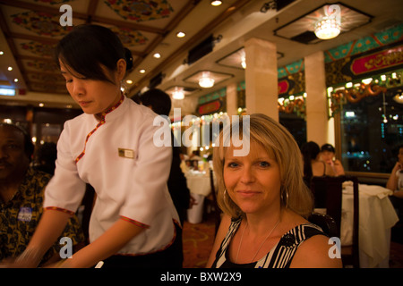 Signora essendo il cibo servito a bordo della barca Jumbo ad Aberdeen, Hong Kong da cameriera Foto Stock