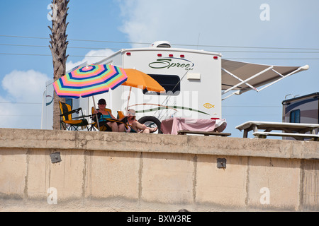 Camper sedersi sul Seawall sotto gli ombrelloni in un RV resort at Beverly Beach, Florida Foto Stock