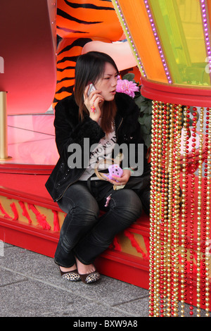 Donna cinese parlando deperately nel telefono cellulare durante il capodanno cinese Foto Stock