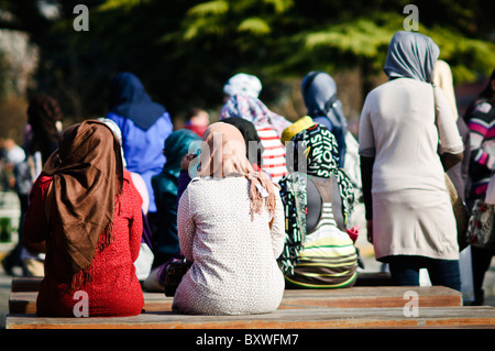 Turisti del Medio Oriente Istanbul Turchia | ISTANBUL, Turchia — Un gruppo di donne con il velo sono sedute di spalle alla telecamera su una panchina di legno nel centro storico di Istanbul, riposandosi in mezzo al traffico costante di turisti e pellegrini della città. L'area attira un gran numero di visitatori da tutto il mondo musulmano, sia per il turismo sightseeing che per il turismo religioso. Foto Stock