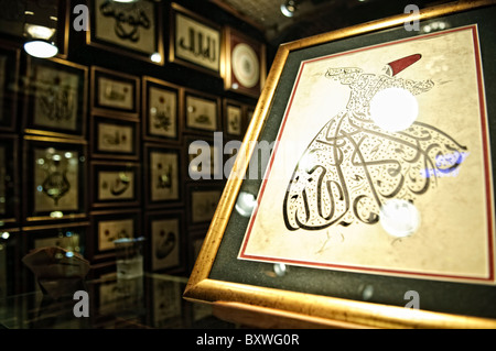 Il vorticoso bazar d'arte calligrafica Derviscia Istanbul / ISTANBUL, Turchia - un negozio d'arte nello storico Grand Bazaar di Istanbul vende illustrazioni, dipinti e calligrafia, con una raffigurazione di ballerini dervisci che sono prominenti in primo piano. I Dervisci Whirling, praticanti della cerimonia sufi Sema associata all'ordine Mevlevi fondato a Konya, sono tra le immagini culturali più iconiche della Turchia e un soggetto frequente per gli artisti del bazar e gli artigiani. Il Grand Bazaar offre da tempo arti decorative e raffinate, accanto al suo tradizionale commercio di tessuti, metalli e ceramiche, r Foto Stock