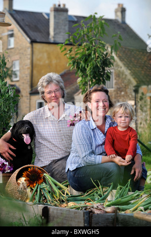 Una famiglia con un raccolto di fresco cipolle tirato da un letto sollevata in un giardino Inglese comune fiori Farm Regno Unito Foto Stock