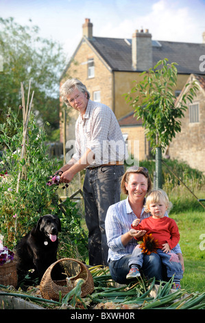 Una famiglia con un raccolto di fresco cipolle tirato da un letto sollevata in un giardino Inglese comune fiori Farm Regno Unito Foto Stock