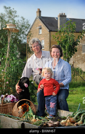 Una famiglia con un raccolto di fresco cipolle tirato da un letto sollevata in un giardino Inglese comune fiori Farm Regno Unito Foto Stock