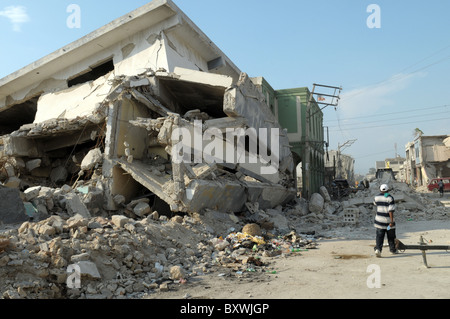 L'uomo cammina passato edificio crollato nel centro di Port au Prince dopo il terremoto di Haiti Foto Stock