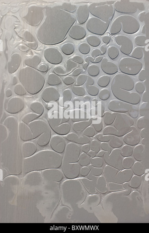 Il gorgogliamento grigio film di materia plastica su una superficie di vetro Foto Stock